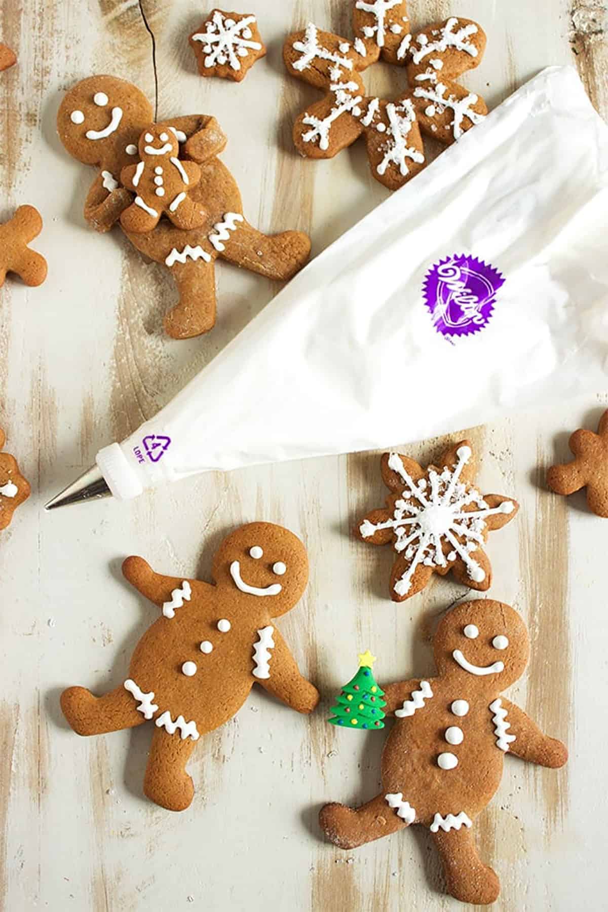 a wilton piping bag filled with royal icing place among gingerbread cookies