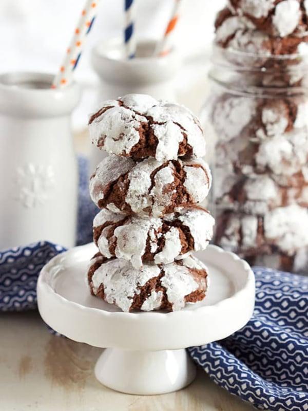 Chocolate crinkle cookies stacked on a cupcake plate on a wood backdrop
