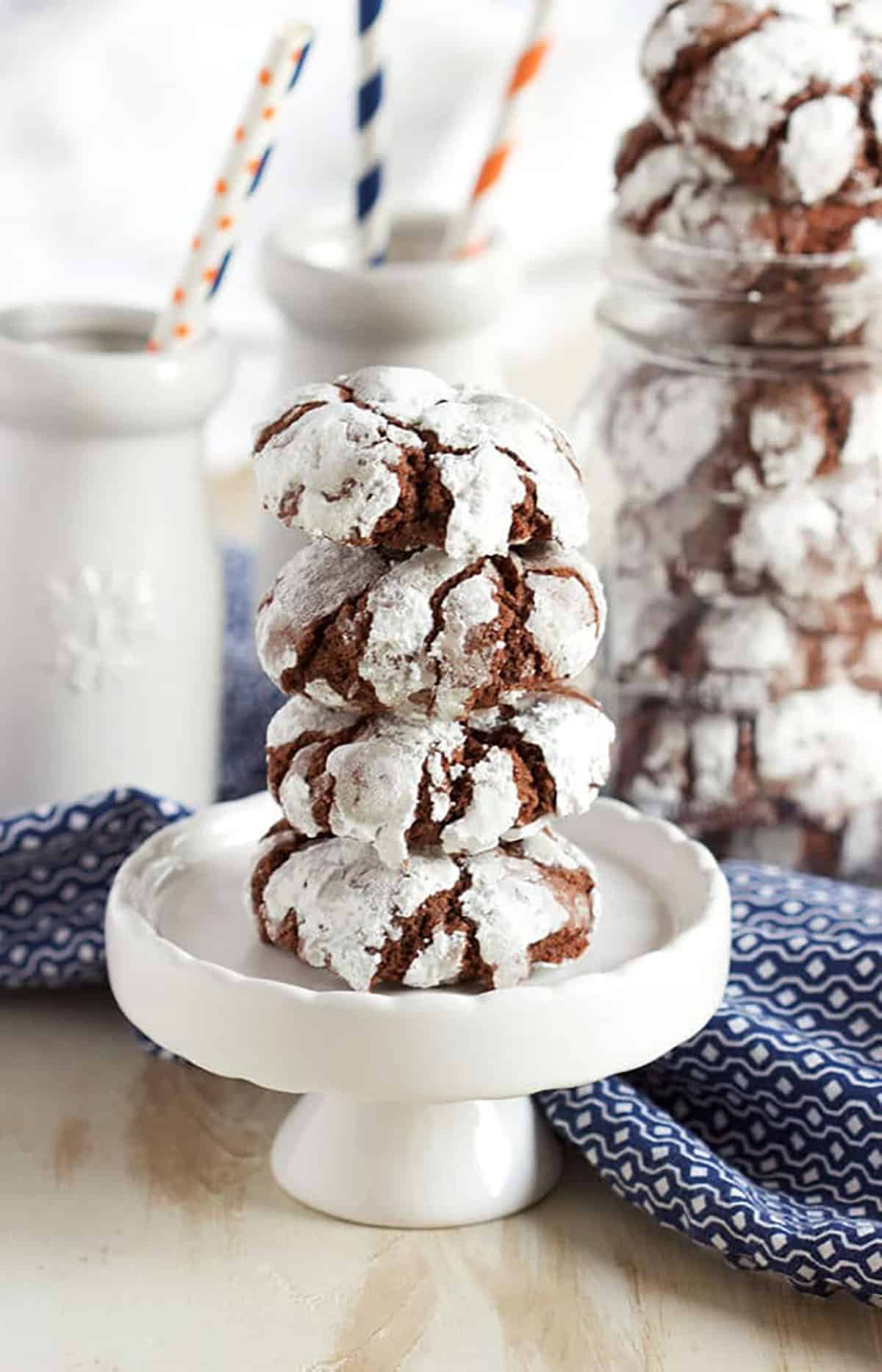 Chocolate crinkle cookies stacked on a cupcake plate on a wood backdrop