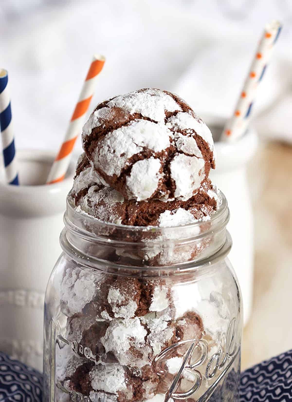 chocolate crinkle cookie on top of as stack of cookies in a jar.