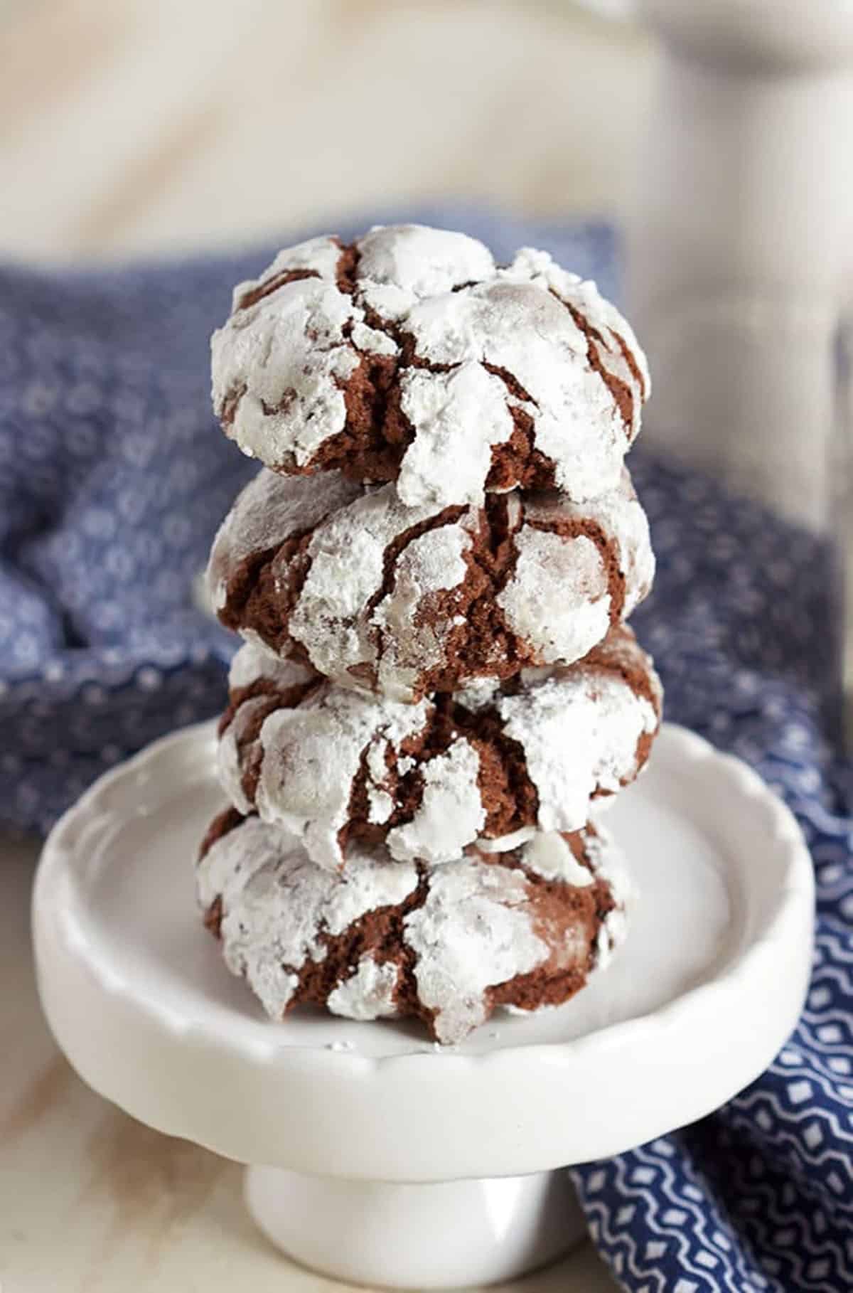 Chocolate Crinkle cookies stacked on a white cupcake plate.