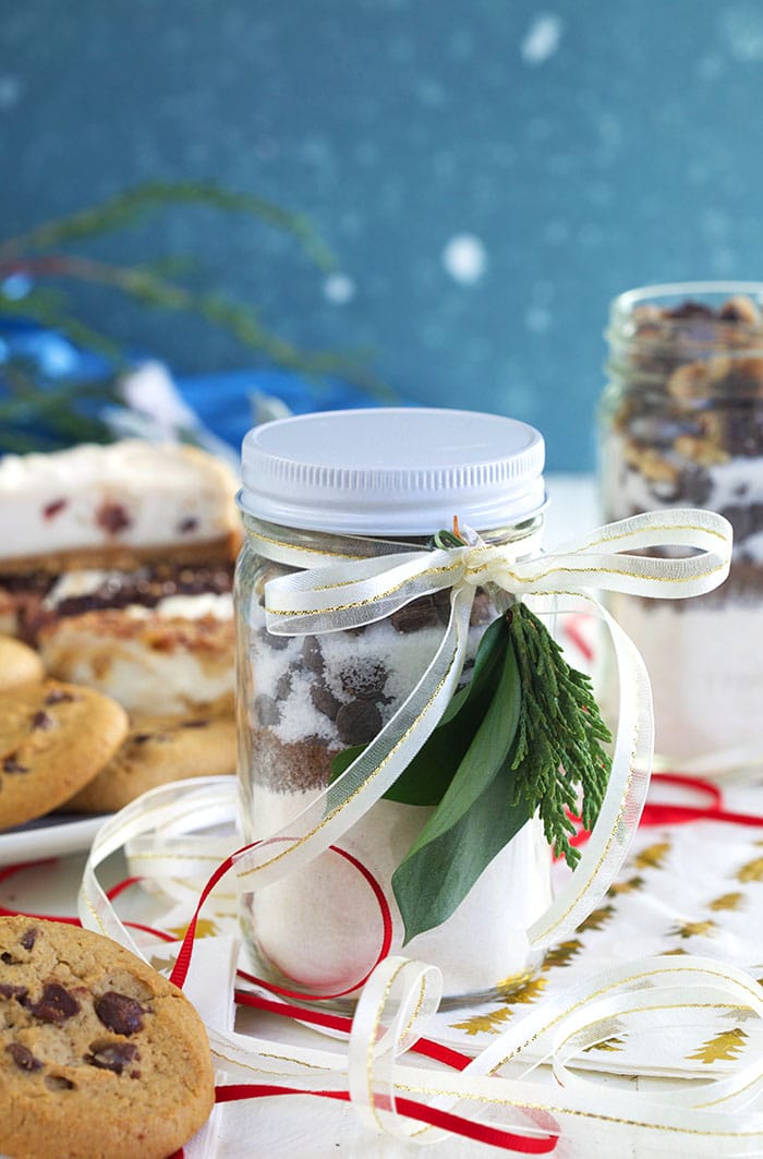 Cookie Mix in a Jar with a ribbon and evergreen fronds tied to the front.