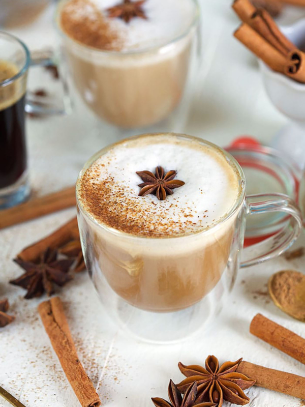Cinnamon stick sit around a glass mug of chai tea.