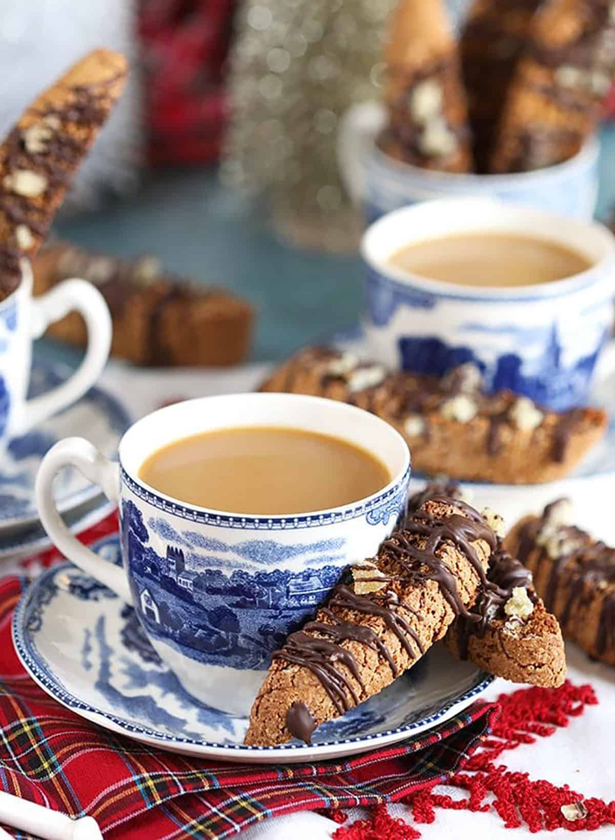 Cup of coffee in a blue and white mug with gingerbread biscotti on the side.