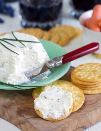 White creamy cheese is spread on a cracker.