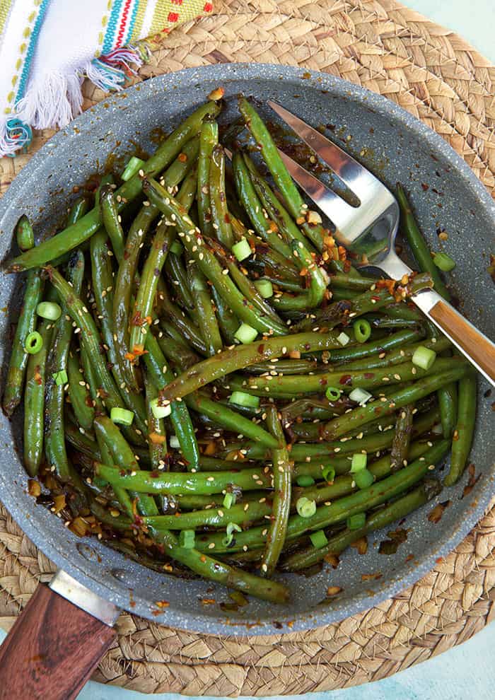 A large serving fork is in a serving of green beans.