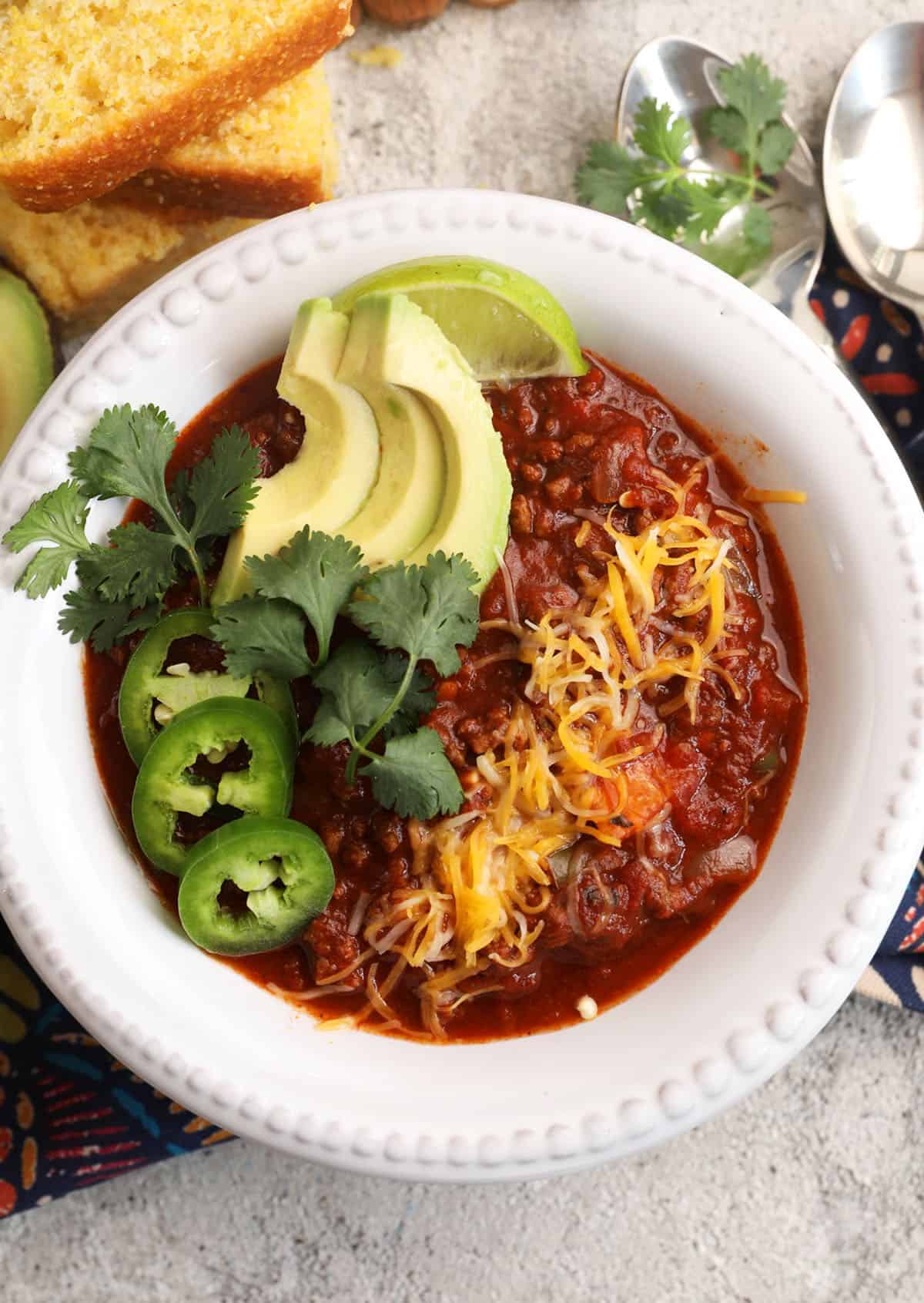 Best chili recipe in bowl with avocado, cilantro, cheese, and jalapeño