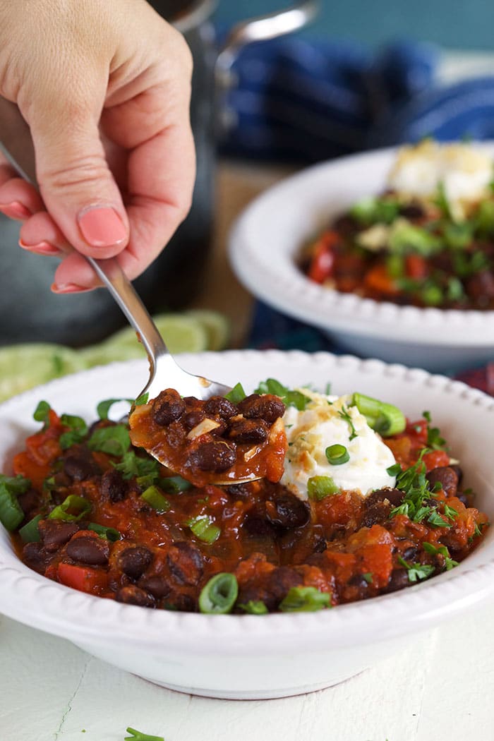 A spoonful of chili is scooped out of a white bowl.