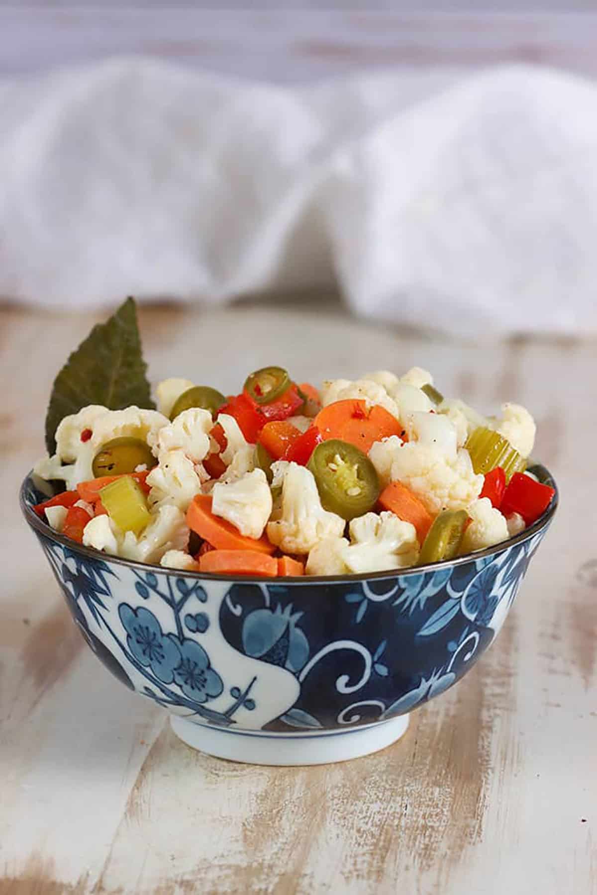 Giardiniera in a blue and white floral bowl with a white napkin in the background.