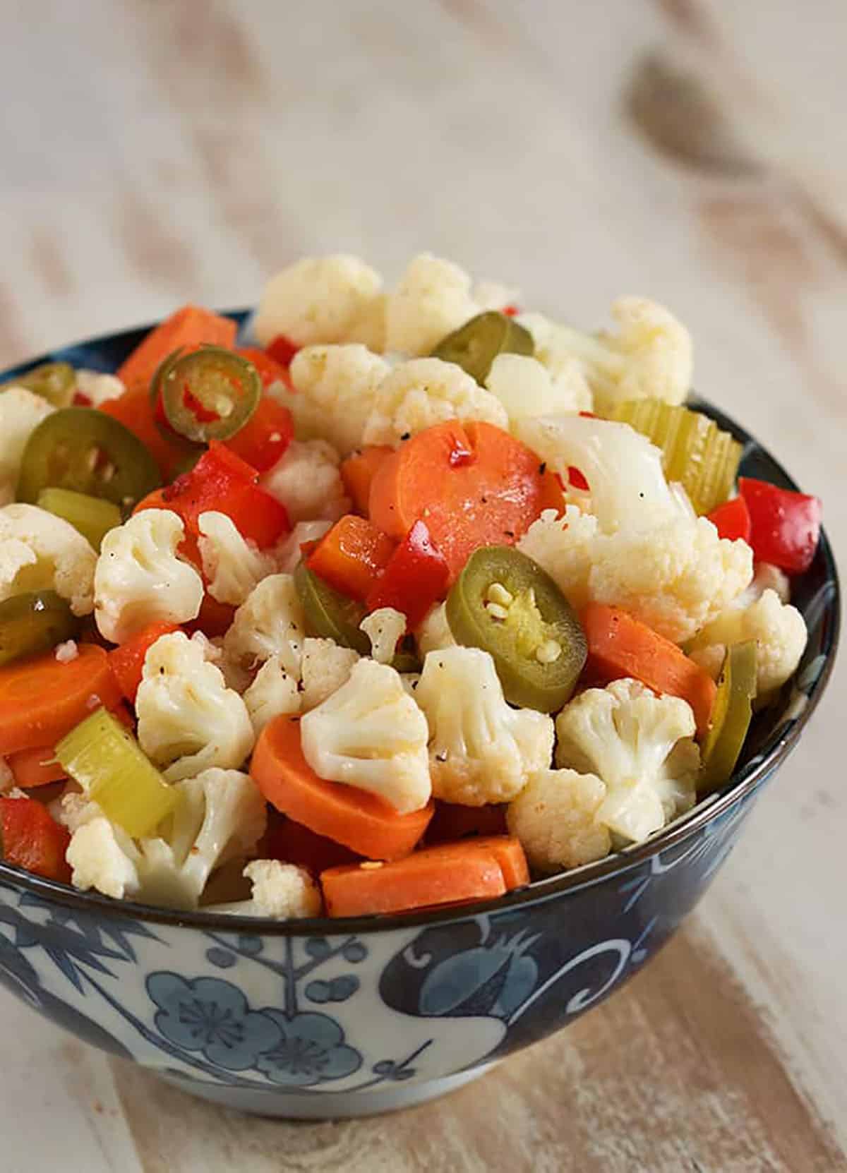 Close up of pickled vegetable giardiniera in a blue and white bowl.