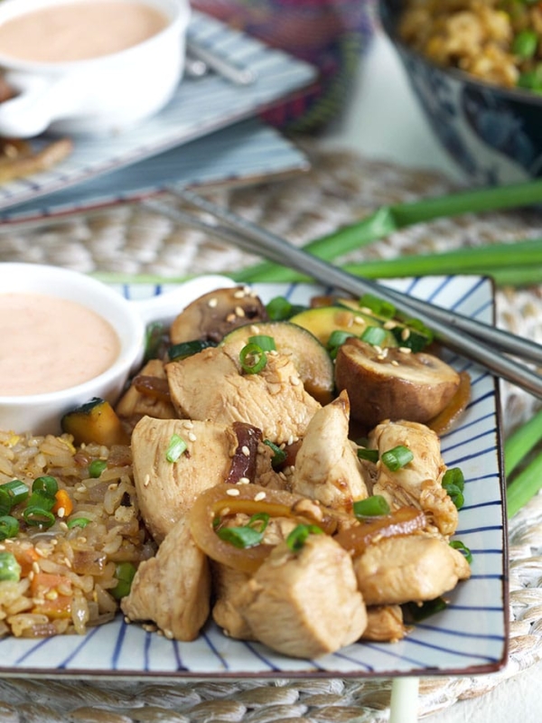 A plate of hibachi chicken is presented with yum yum sauce and chopsticks.