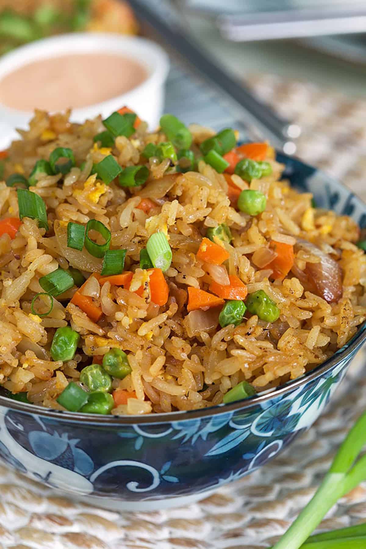 A close up image shows fried rice garnished with freshly chopped green onions.