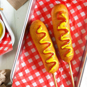 Overhead shot of corn dogs with ketchup and mustard on them.