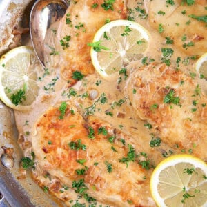 lemon chicken scallopini in a skillet with lemon slices on top
