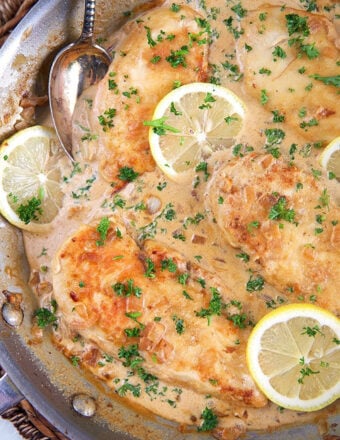 lemon chicken scallopini in a skillet with lemon slices on top