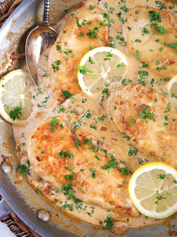lemon chicken scallopini in a skillet with lemon slices on top