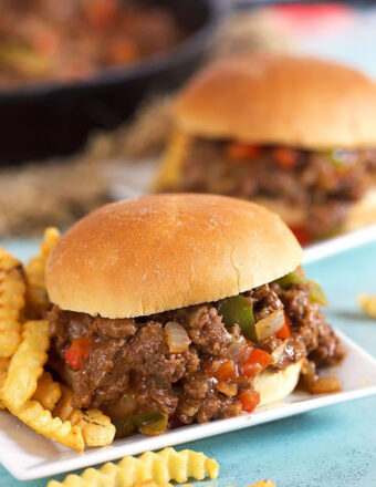 Philly Cheesesteak Sloppy Joe on a white square plate with crinkle cut fries.