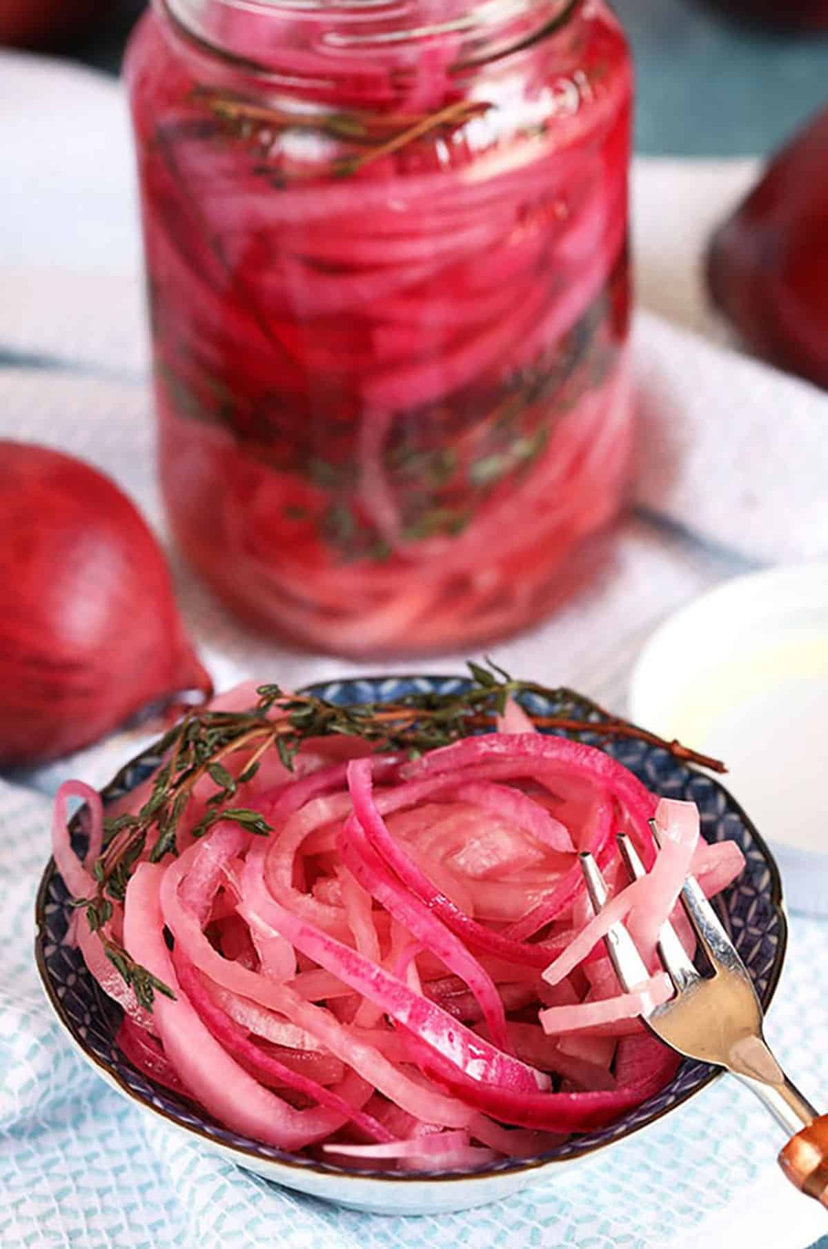 Mexican pickled onions in a blue and white dish with a copper fork.