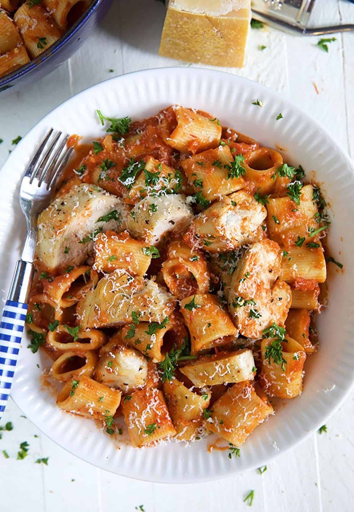 A serving of spicy chicken rigatoni is in a white bowl.