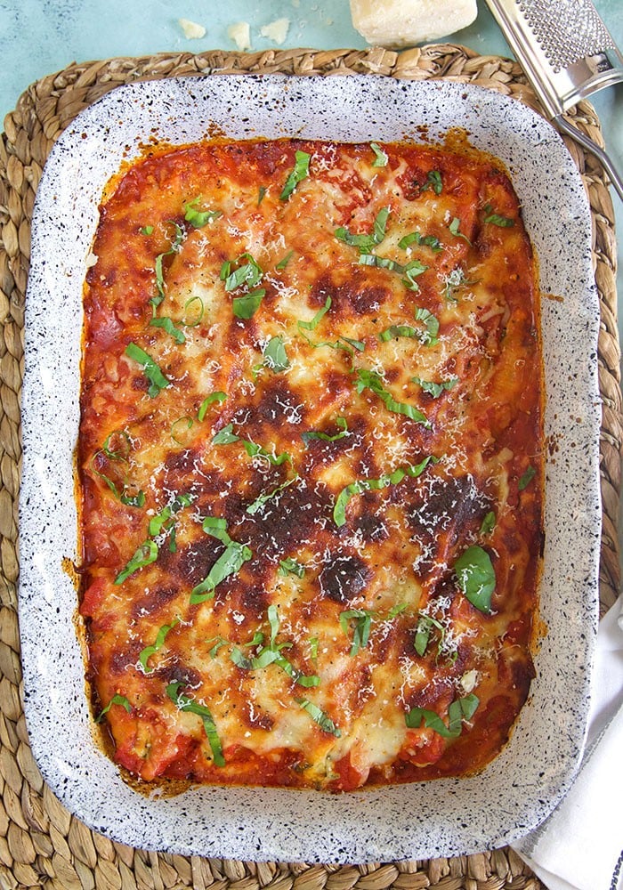 A fully baked dish of stuffed shells is garnished with freshly cut parsley.