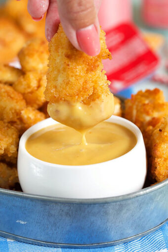 Chick Fil A Sauce in a white dish with a chicken nugget being dipped into it.