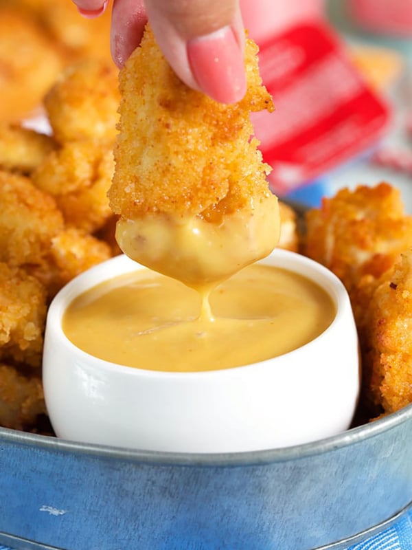 Chick Fil A Sauce in a white dish with a chicken nugget being dipped into it.