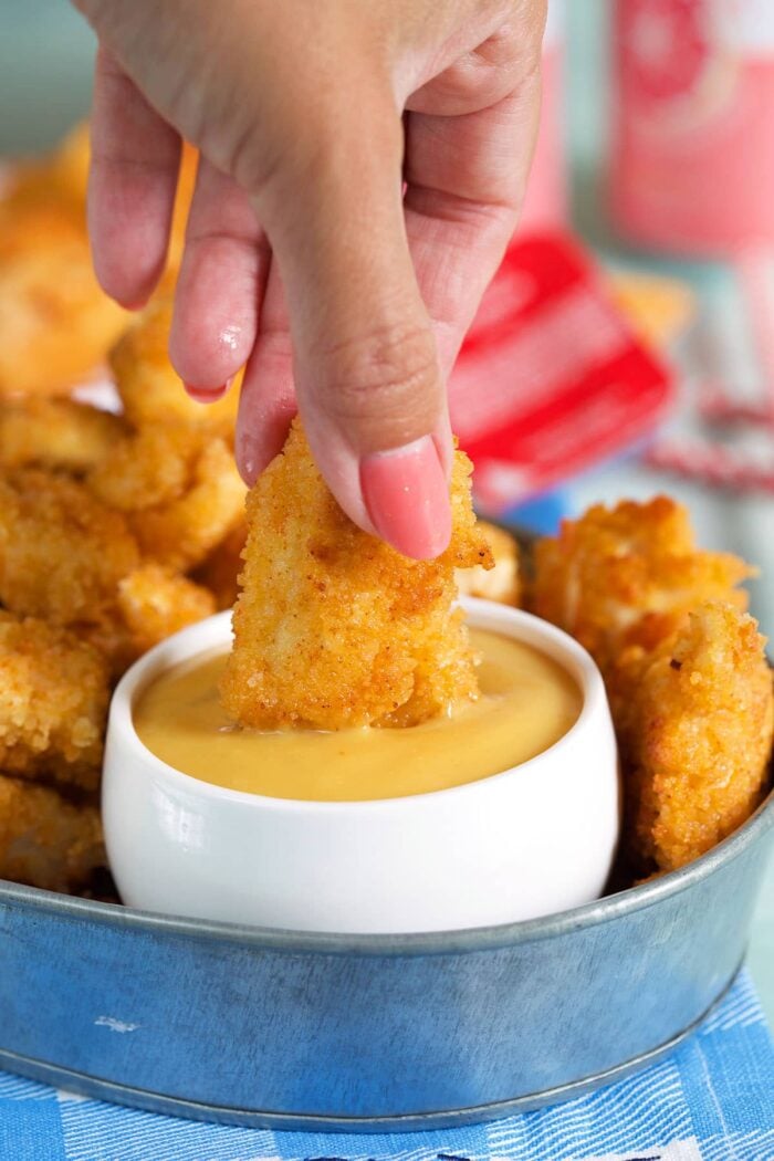 A chicken nugget is being dipped into a small bowl of chick fil a sauce.