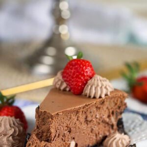 Slice of Chocolate Cheesecake with a strawberry on top and bite on a fork.