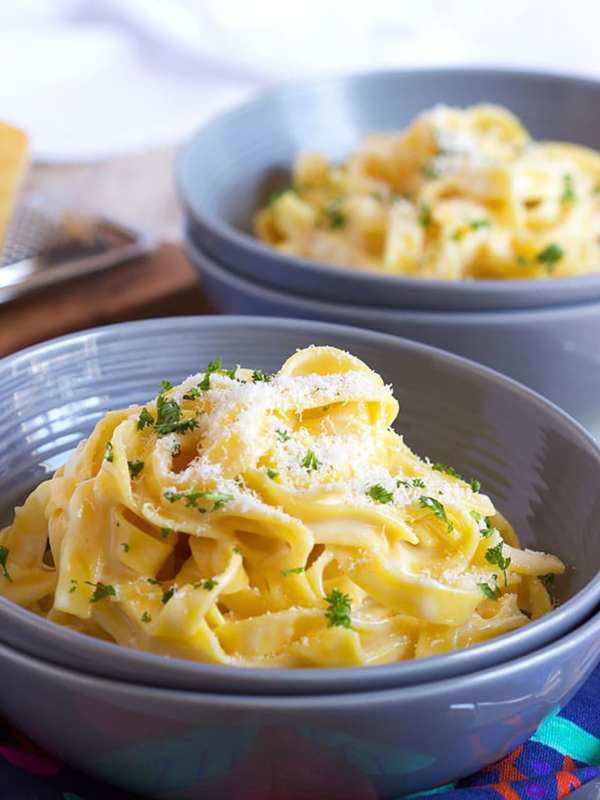 Fettuccine Alfredo in a blue bowl with cheese sprinkled on top