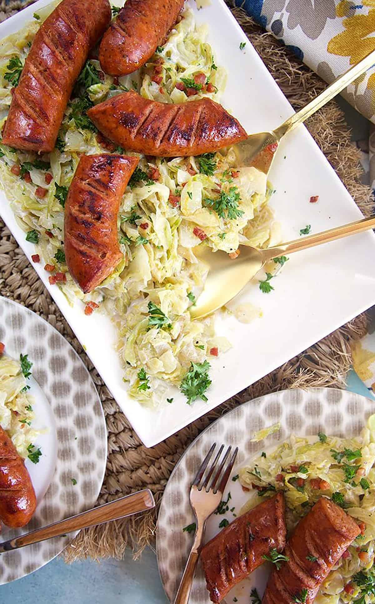 Overhead shot of fried cabbage and kielbasa on a white platter.