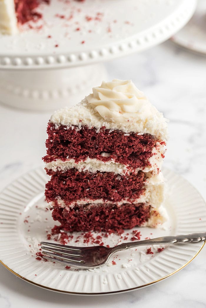 Slice of red velvet cake on a white plate with a fork.