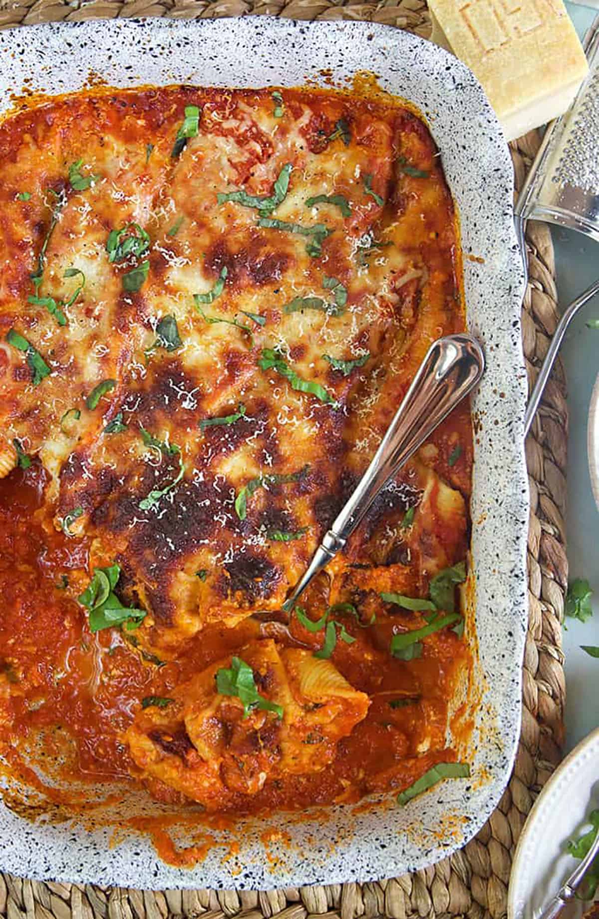 A large baking dish contains a fully baked dinner serving of stuffed shells.
