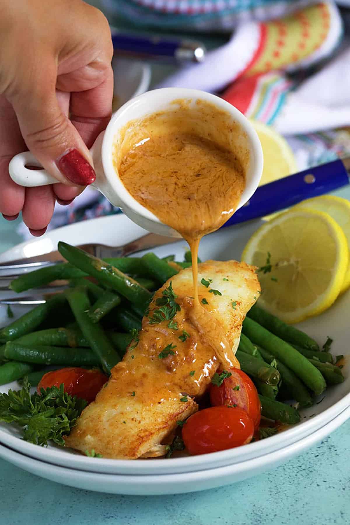 Brown butter sauce is poured over freshly cooked halibut. 
