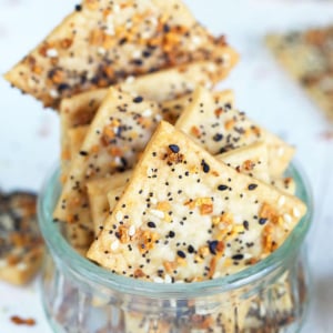 Several homemade crackers are placed in a tiny glass cup on a white surface.