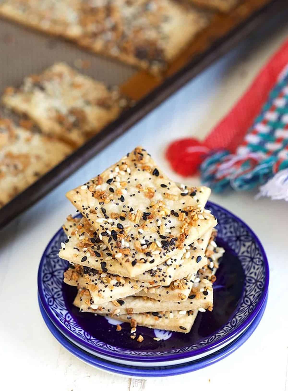 A large stack of everything crackers are stacked on a blue plate.