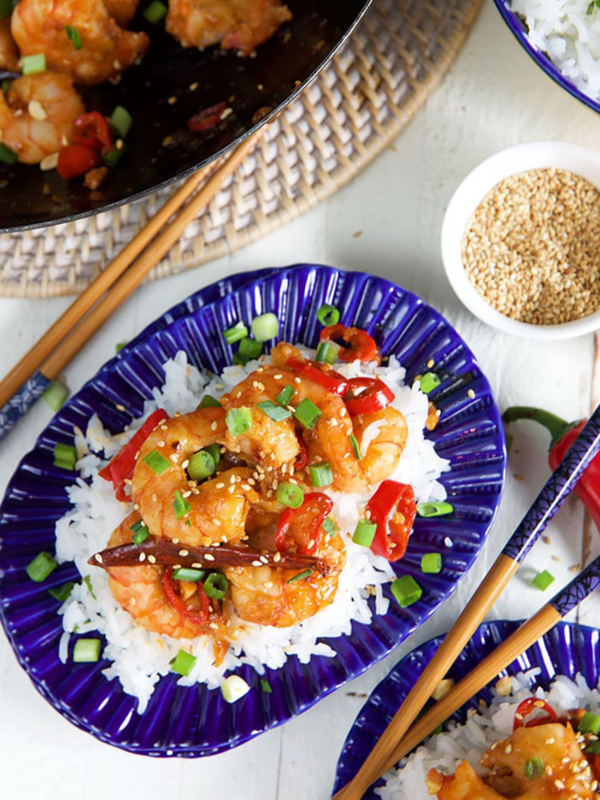 Chopsticks are placed next to a plate full of Szechuan shrimp.