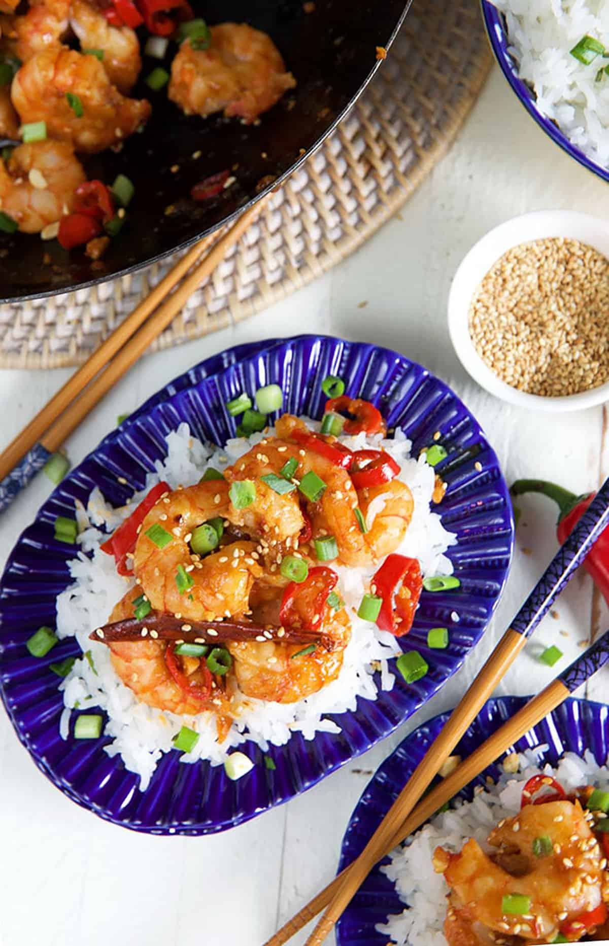 Chopsticks are placed next to a plate full of Szechuan shrimp.