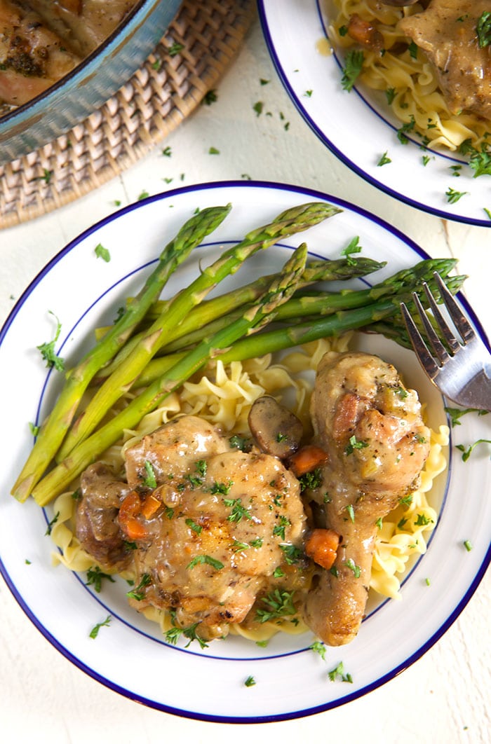 A plate of chicken fricassee and asparagus is ready to be eaten.