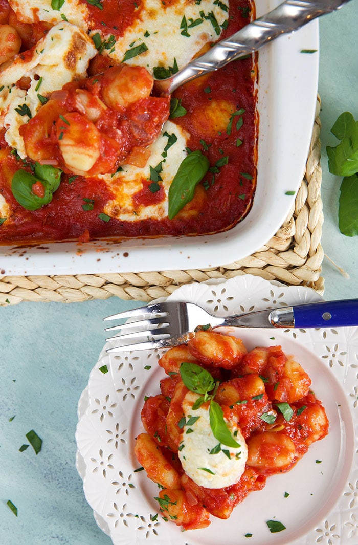 A fork is placed on a plate that's topped with fresh gnocchi and tomato sauce.