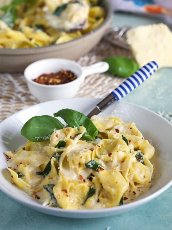 A white bowl contains a serving of asiago tortellini.