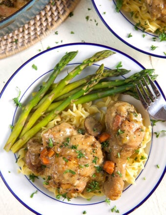 A fork sits on a plate with asparagus and chicken, ready to be eaten.