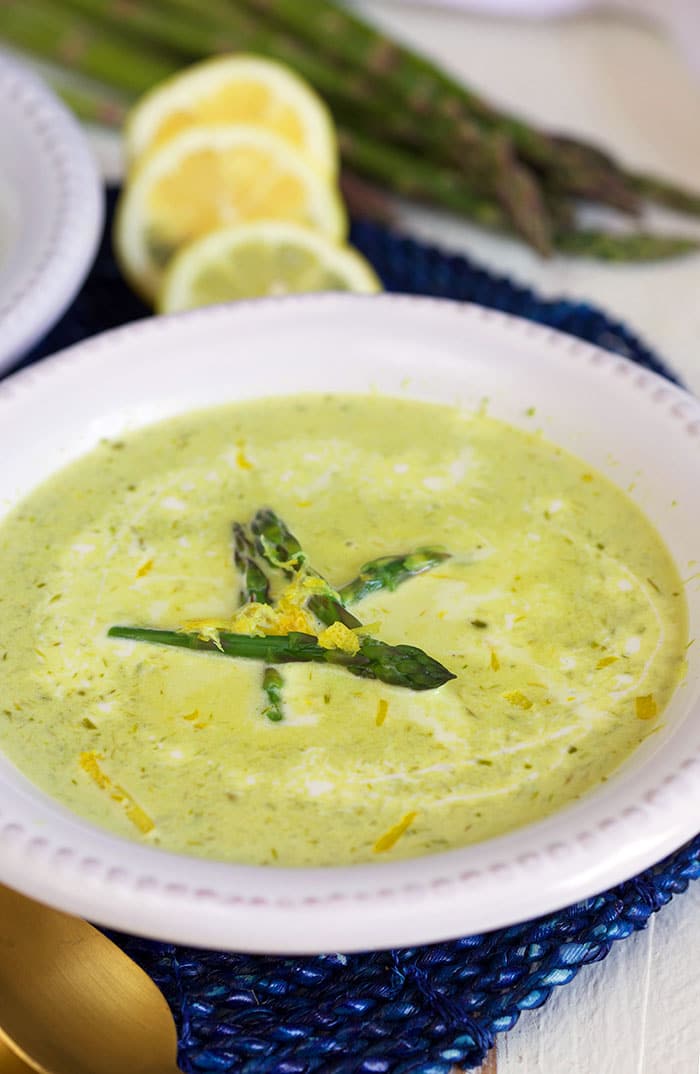 A white bowl is filled with green asparagus soup.
