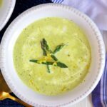A few pieces of cooked asparagus garnish a bowl filled with creamy soup.