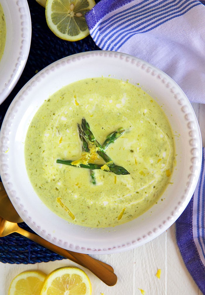 A few pieces of cooked asparagus garnish a bowl filled with creamy soup.