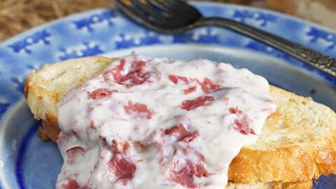 Close up of creamed chipped beef on toast on a blue plate.