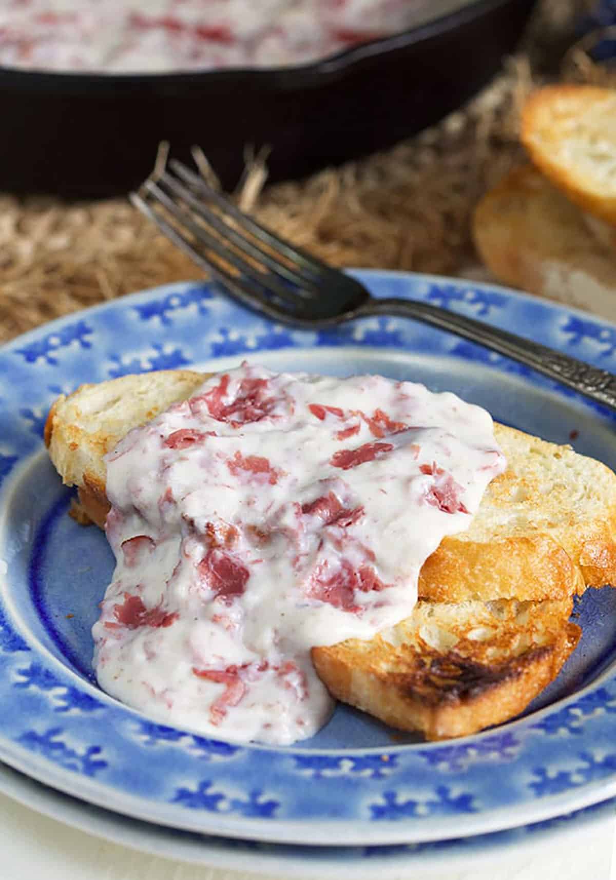 Close up of creamed chipped beef on toast on a blue plate.