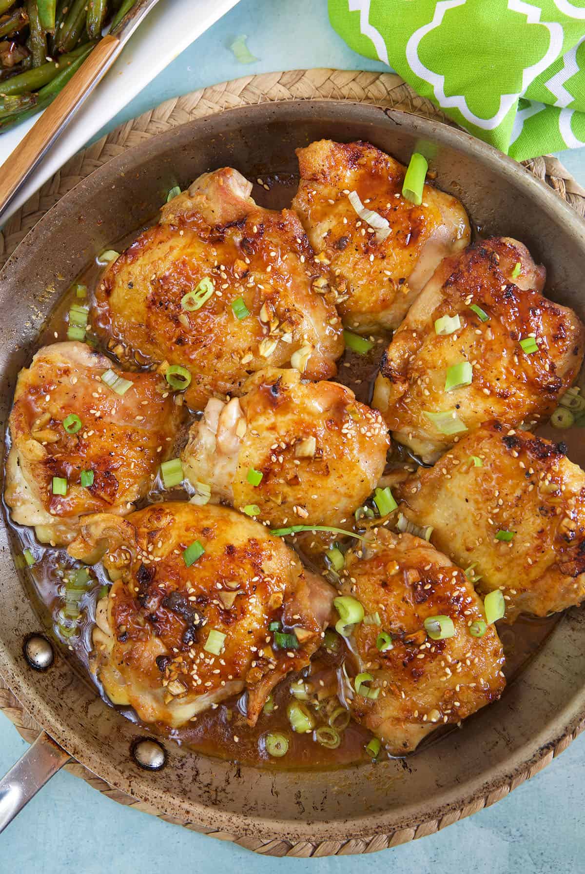 A batch of chicken thighs are in a large skillet.