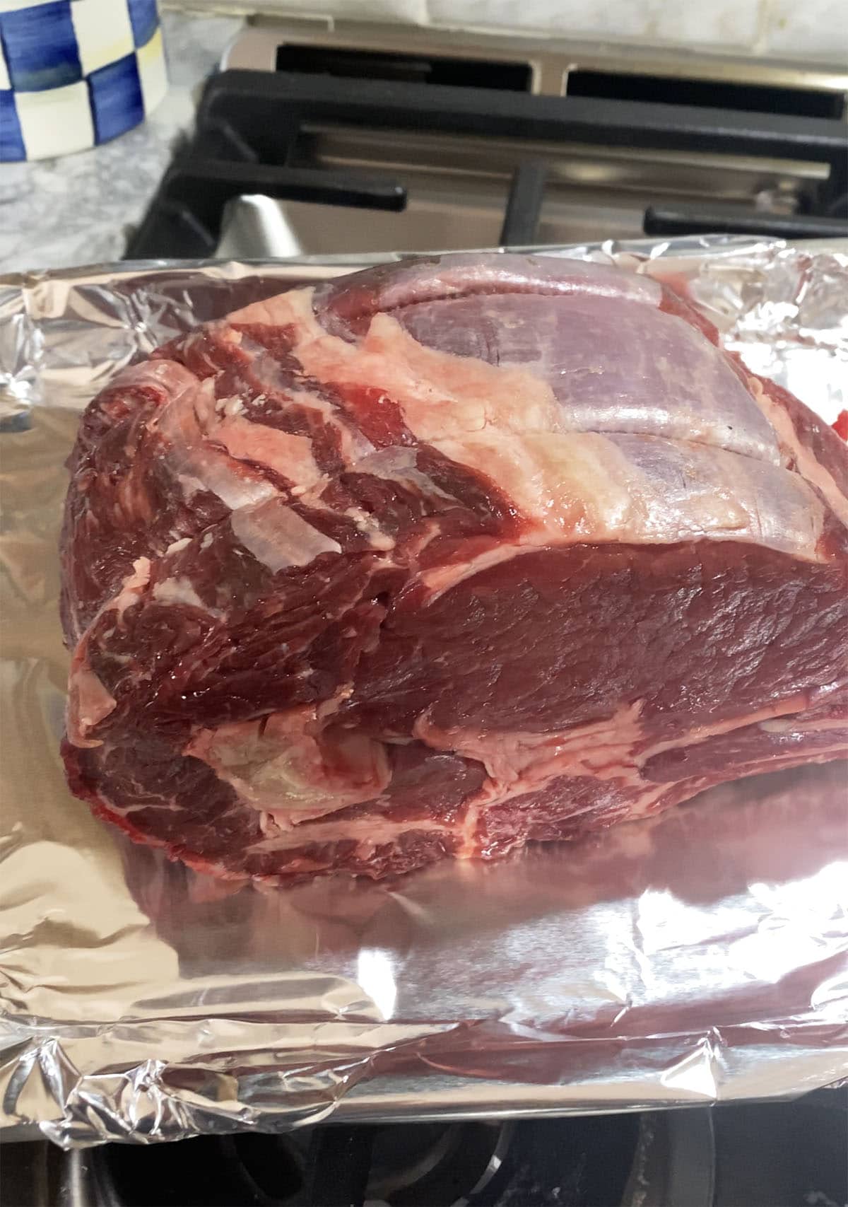 A large cut of uncooked prime rib is placed on a prepared baking dish.