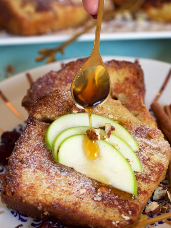 Maple syrup is being drizzled onto a piece of French toast.