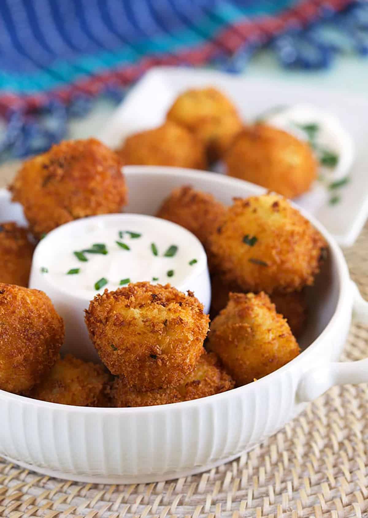 A large white bowl filled with croquettes is ready to be served. 